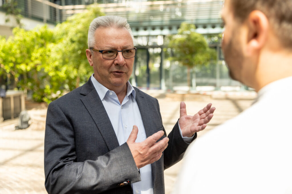 Peter Erb und Tobias Enders im Gespräch im Innenhof eines modernen Gebäudes