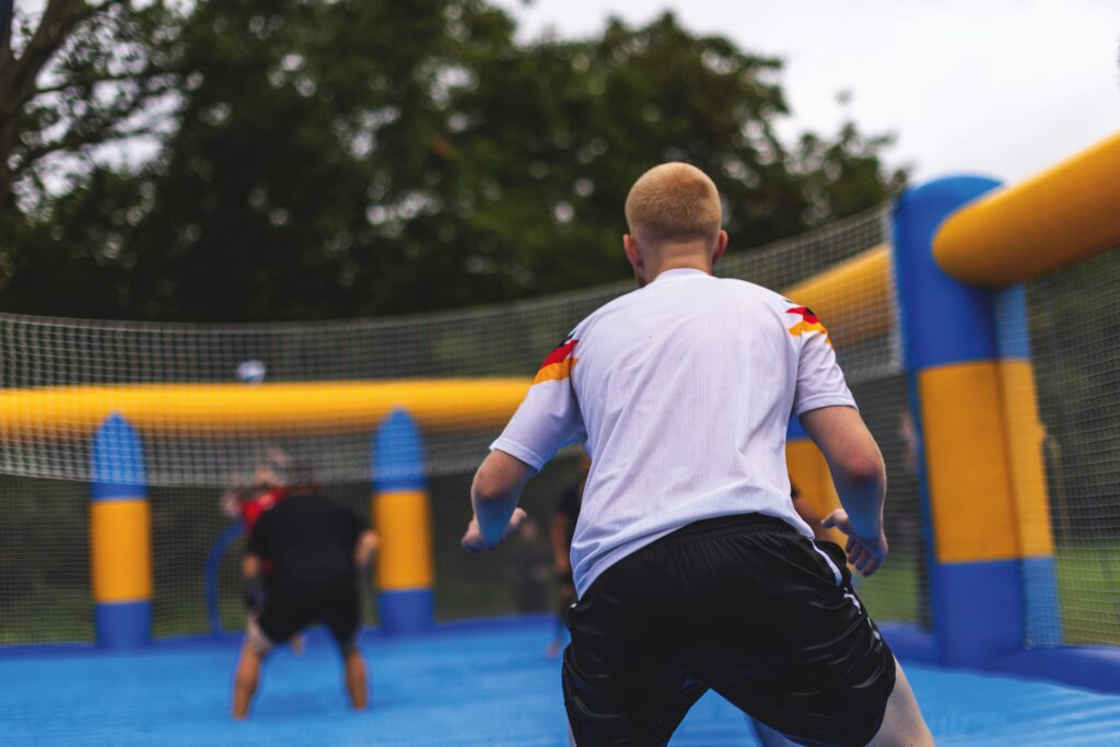 Zwei junge Männer spielen Beachvolleyball auf einem aufblasbaren Feld während der Azubi-Einführungswoche