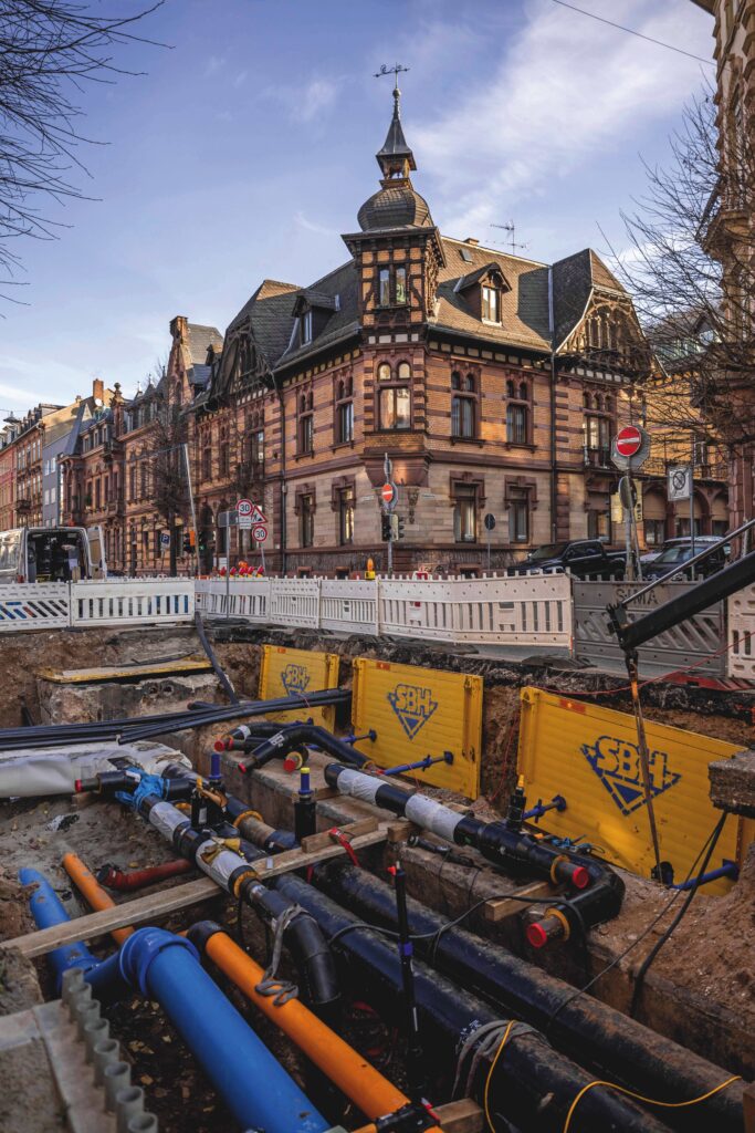 Baustelle mit freigelegten Versorgungsleitungen vor historischer Gebäudefassade an der Rohrbacher Straße