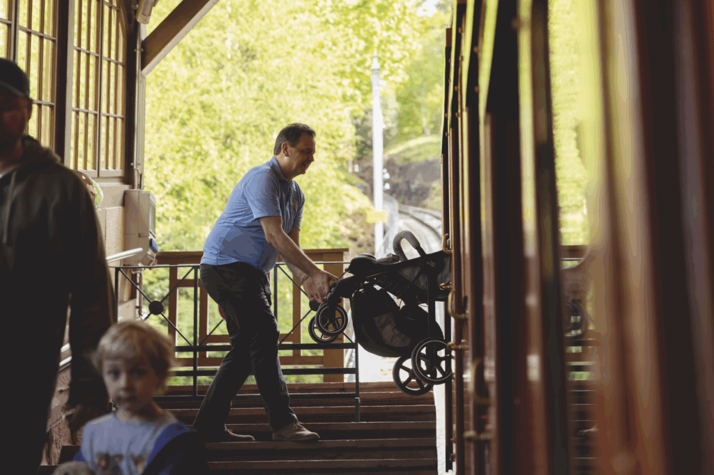 Martin Wenger, Wagenbegleiter bei den Heidelberger Bergbahnen, schiebt einen Kinderwagen eine Treppe hinauf in einer Bergbahnstation