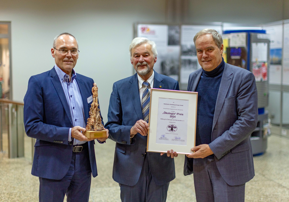 Hans-Joachim Ritter überreicht Urkunde und Ökologia-Skulptur an Prof. Dr. Eckart Würzner und Prof. Dr. Rudolf Irm in formeller Umgebung