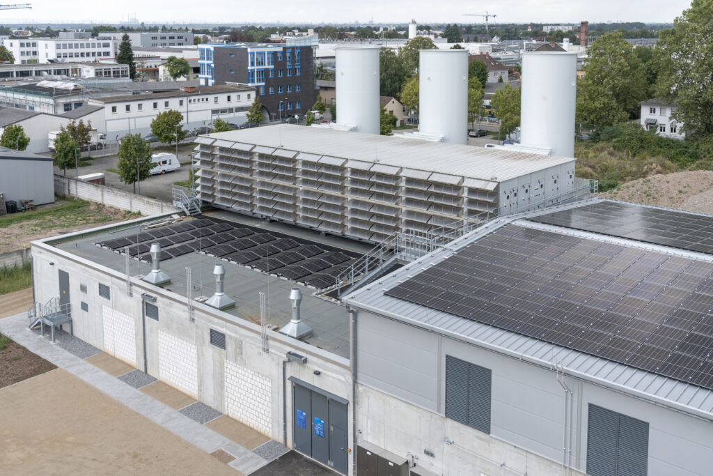 iKWK-Anlage mit drei großen zylindrischen Luftheizwerken auf dem Dach eines Industriegebäudes in einem Gewerbegebiet